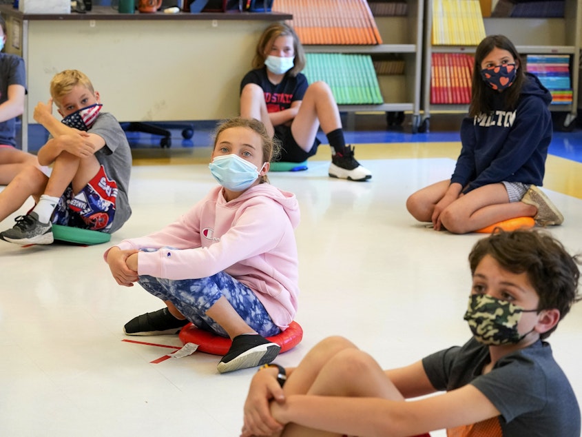 caption: Fifth-graders wearing face masks sit at proper social distancing during a music class at the Milton Elementary School in Rye, N.Y., May 18, 2021. The COVID-19 pandemic that shuttered classrooms set back learning in some U.S. school systems by more than a year, with children in high-poverty areas affected the most, according to data shared with The Associated Press.