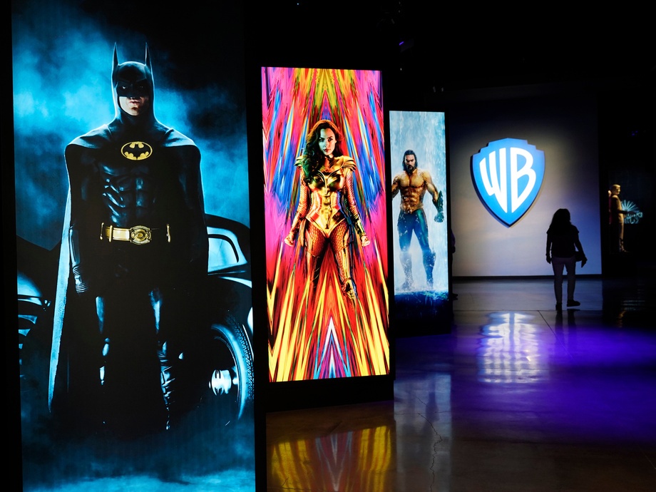 caption: A visitor walks past portraits of DC Comics superheroes as she enters the "Action and Magic Made Here" interactive experience at the Warner Bros. Studio Tour Hollywood media preview on June 24, 2021, in Burbank, Calif.