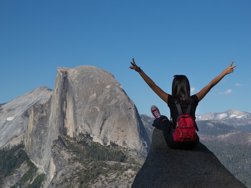 caption: People take pictures at Yosemite National Park's Glacier Point with Half Dome as a backdrop in July 2019.