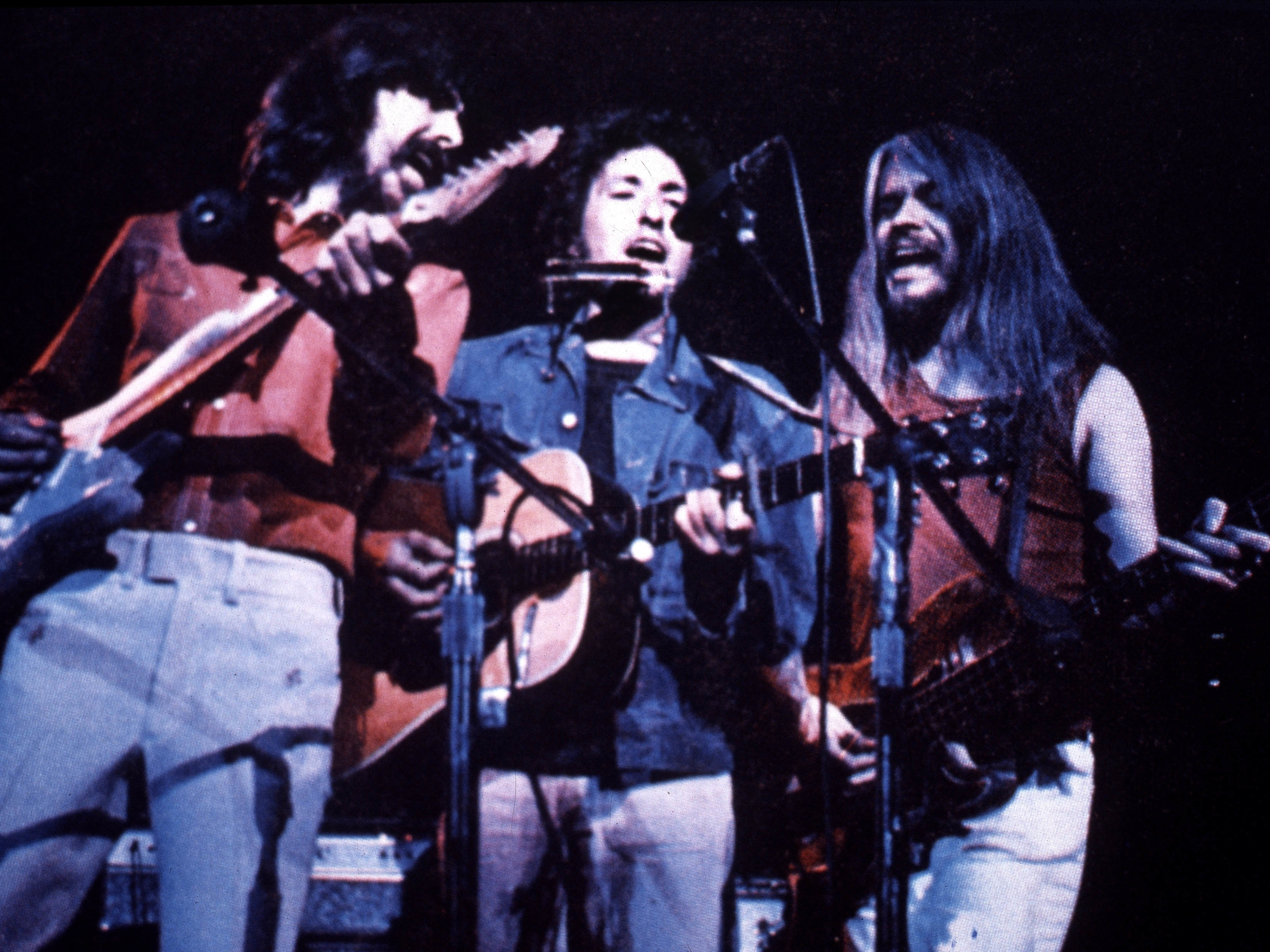 caption: George Harrison, Bob Dylan and Leon Russell perform at the Concert for Bangladesh in 1971.