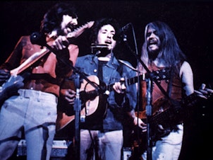 caption: George Harrison, Bob Dylan and Leon Russell perform at the Concert for Bangladesh in 1971.