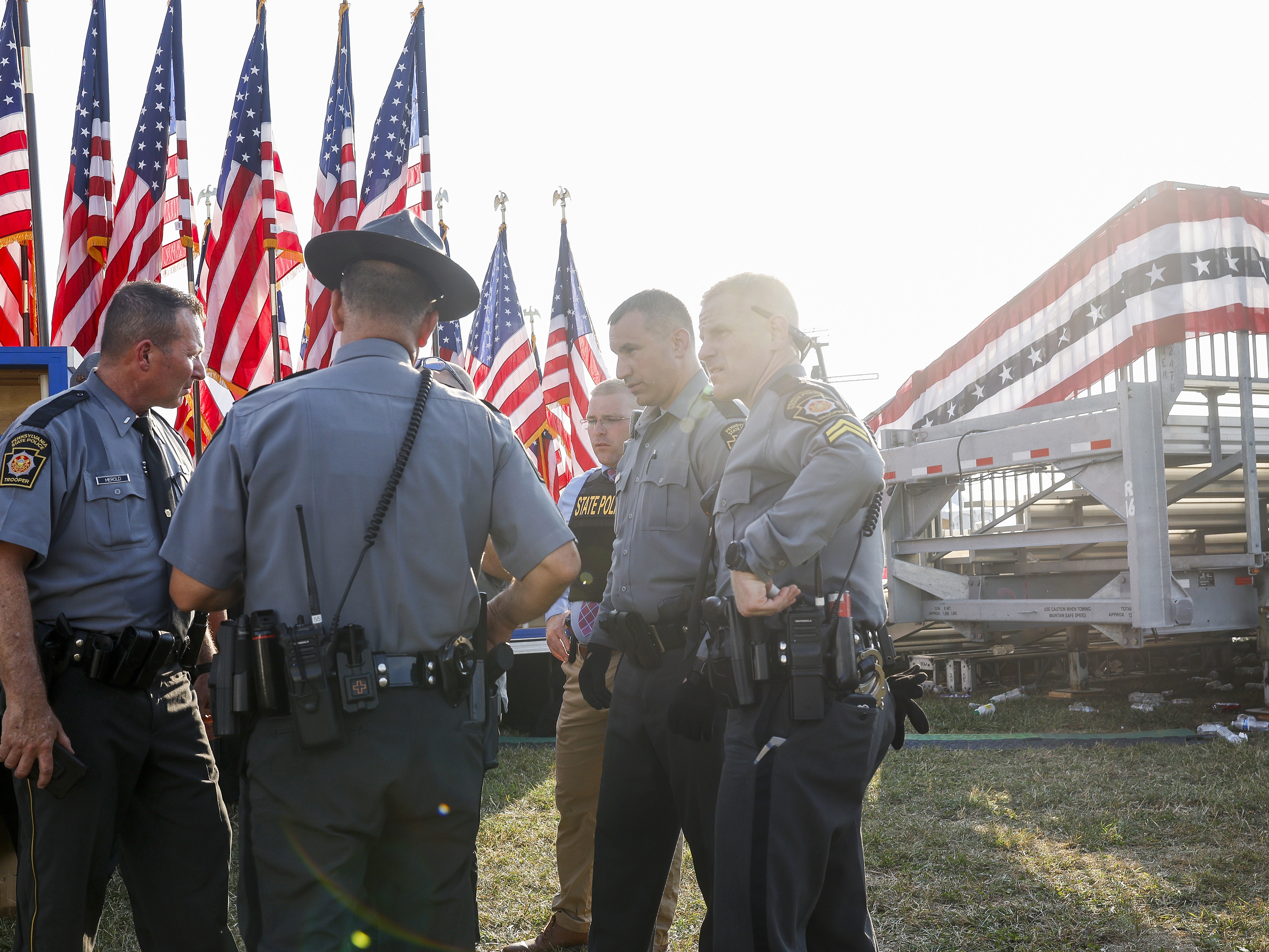 caption: Law enforcement agents stand near the stage of a campaign rally for former President Donald Trump after a failed assassination attempt on Saturday in Butler, Pa. Conspiracy theories and violent rhetoric have surged since the shooting. 