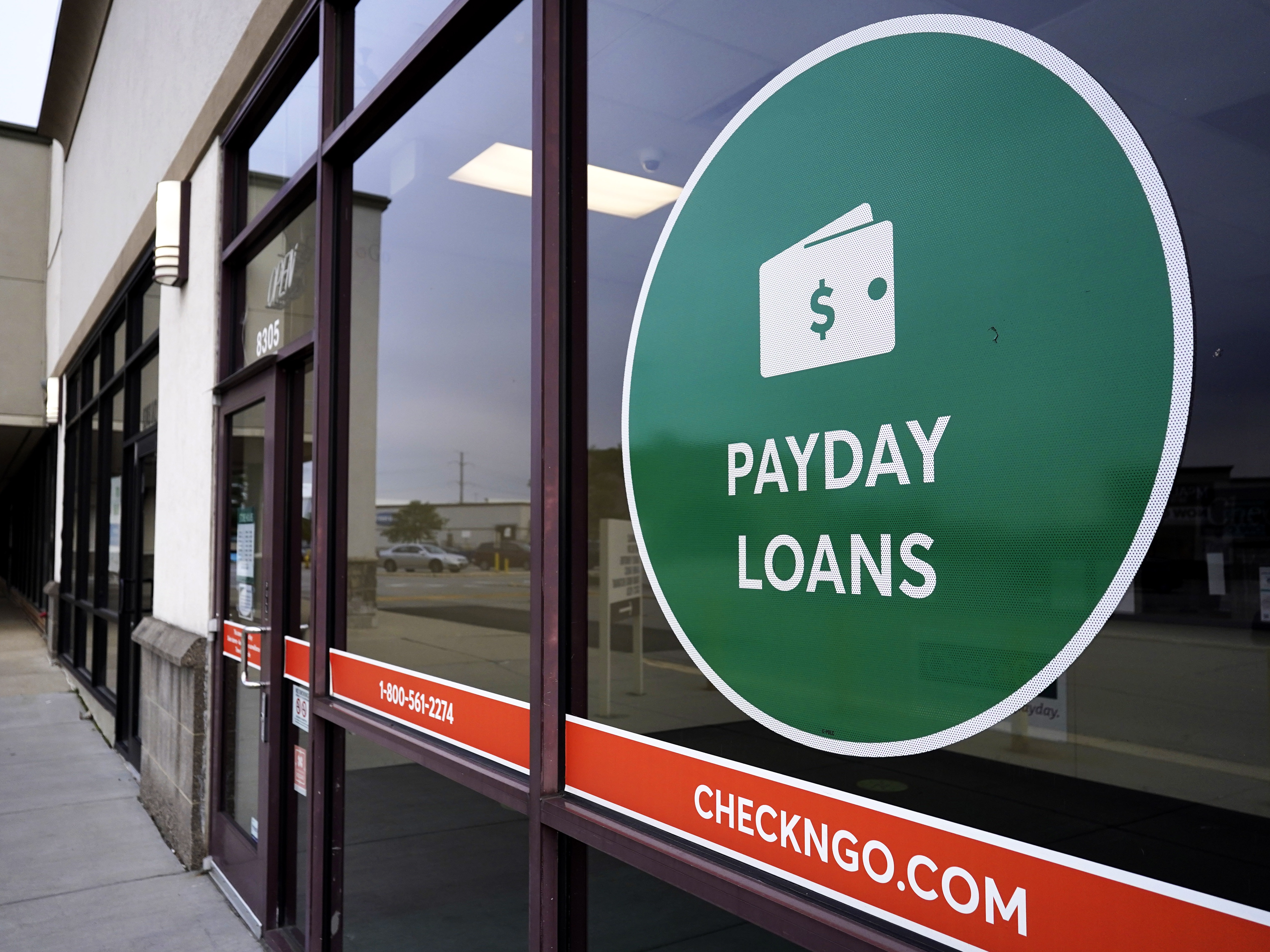 caption: A "payday loans" sign is displayed at a Check 'n Go in Niles, Ill., in 2021.