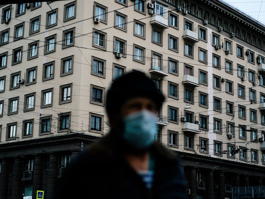 caption: A man wearing a face mask walks in Moscow during a strict lockdown to stop the spread of the coronavirus on April 15, 2020.