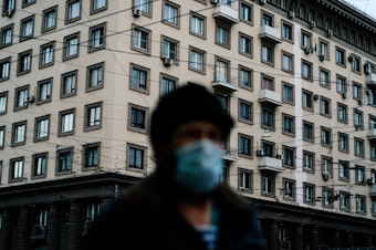 caption: A man wearing a face mask walks in Moscow during a strict lockdown to stop the spread of the coronavirus on April 15, 2020.