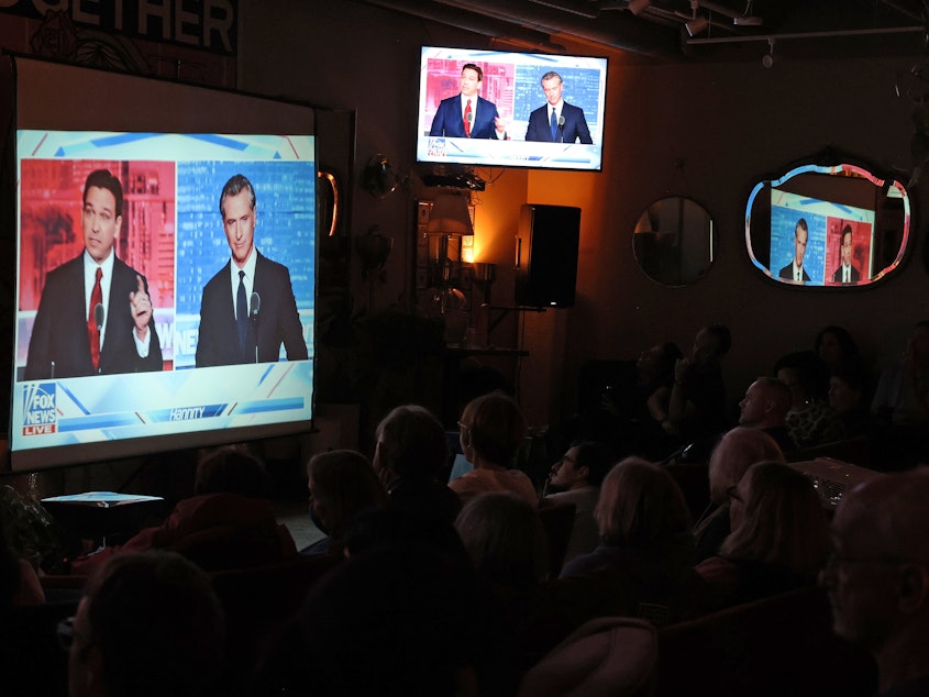 caption: People gather in San Francisco to watch a debate on Fox News between California Gov. Gavin Newsom and Florida Gov. Ron DeSantis.