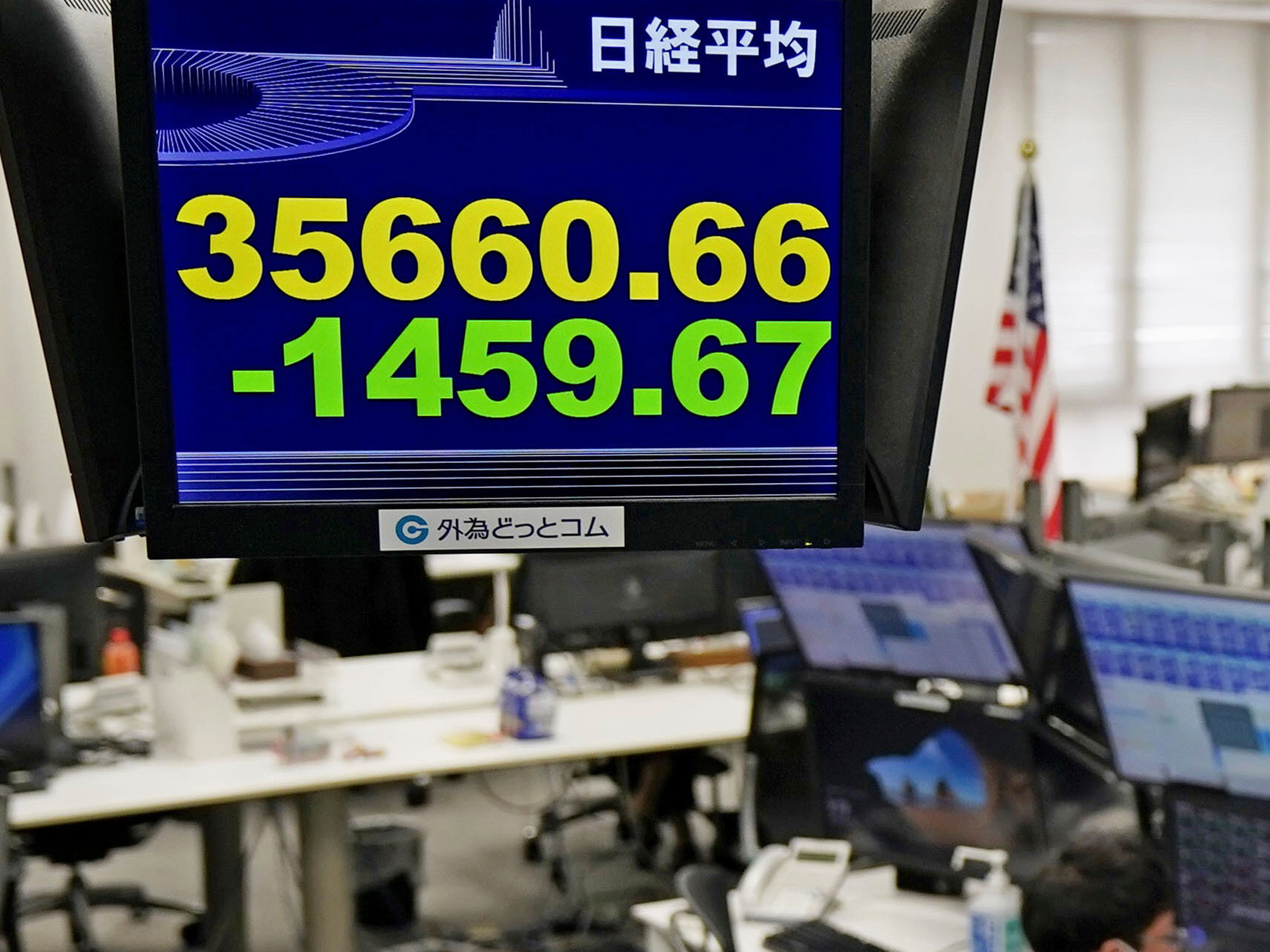 caption: A currency trader works under an electronic stock board at a foreign currency trading firm in Tokyo Monday, March 31, 2025.