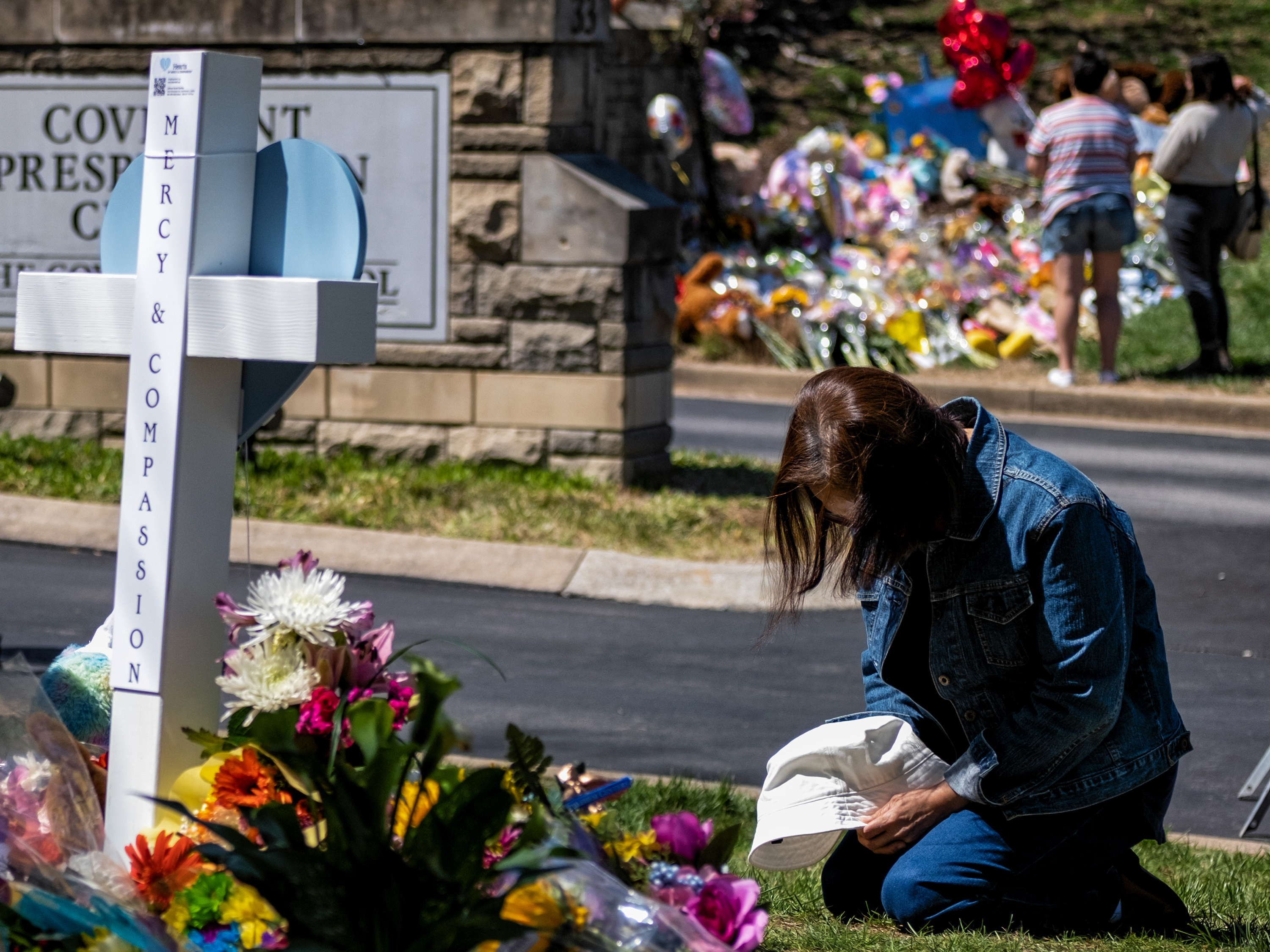 caption: A woman prays at a makeshift memorial for those killed in a mass shooting at the entrance of The Covenant School on March 29, 2023 in Nashville, Tennessee. Three students and three adults were killed by the 28-year-old shooter on Monday.
