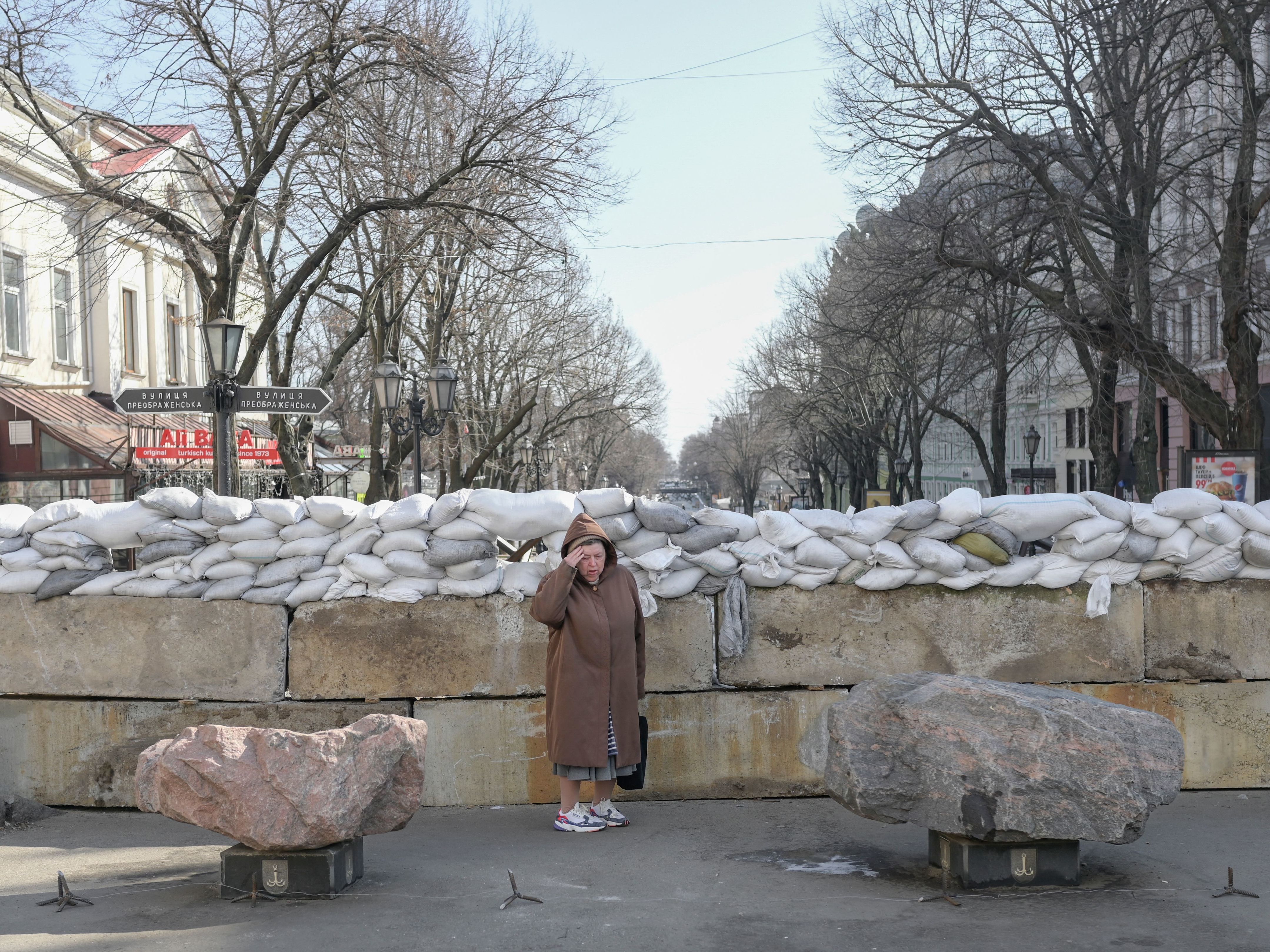 caption: <strong>March 13</strong>: A resident stands next to a sandbag barricade in Odessa.