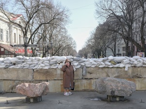 caption: <strong>March 13</strong>: A resident stands next to a sandbag barricade in Odessa.