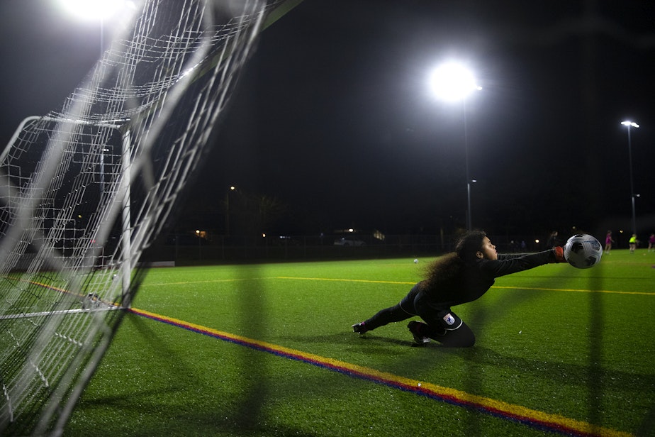 caption: Kirra Sotheron, 11, dives for the soccer ball during introductory goal keeper training with Seattle Reign Academy on Monday, January 29, 2024, at North SeaTac Park.