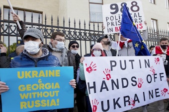 caption: Georgian activists hold posters as they gather in support of Ukraine in front of the Ukrainian Embassy in Tbilisi, Georgia on Sunday, Jan. 23. The British government on Saturday accused Russia of seeking to replace Ukraine's government with a pro-Moscow administration.