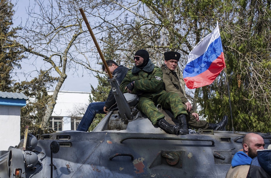 caption: Crimean self-defense force members sit atop an APC with a Russian flag outside the Ukrainian navy headquarters stormed by Crimean self-defense forces in Sevastopol, Crimea, Wednesday, March 19, 2014.