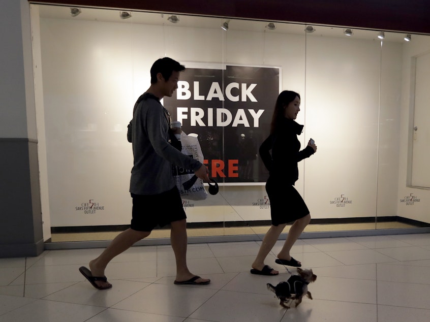 caption: Shoppers walk past a Saks Fifth Avenue outlet store in Miami on Black Friday. Millennials have lower earnings, fewer assets and less wealth, a new Federal Reserve study says.