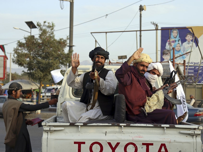 caption: Taliban fighters wave from the back of a pickup truck, in Kabul, Afghanistan, Monday, Aug. 30, 2021. Many Afghans are anxious about the Taliban rule and are figuring out ways to get out of Afghanistan.