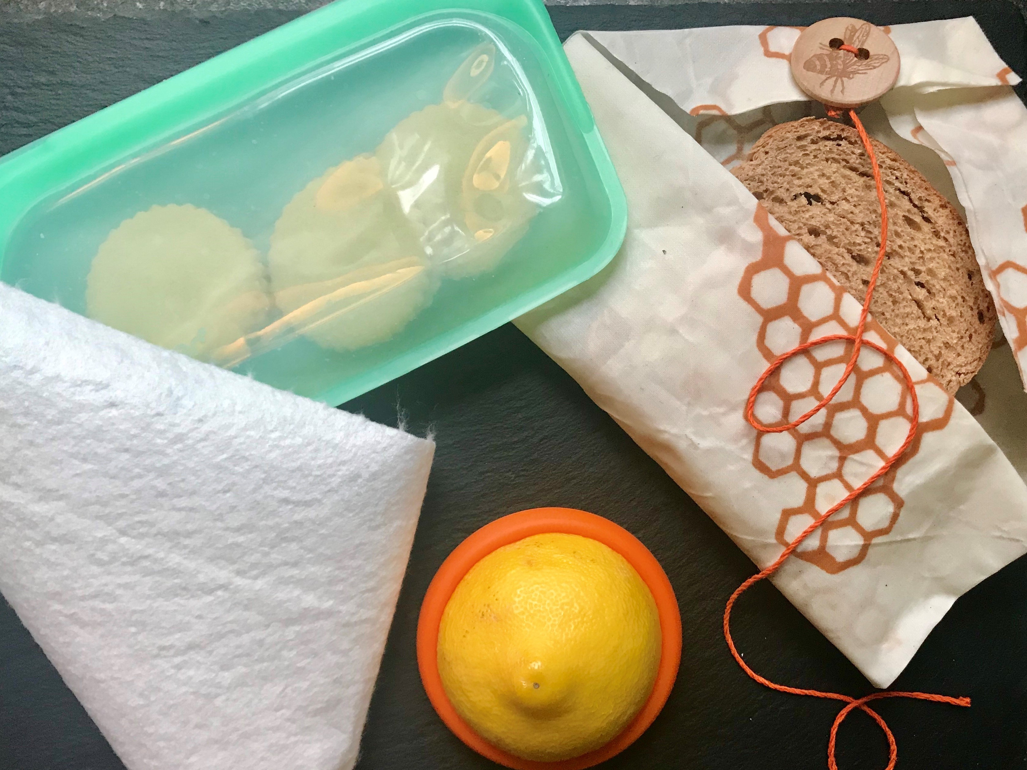 caption: Last year, the author set about reducing her reliance on single-use disposables in the kitchen. Above are some of the tools she has adopted for food storage: a heavy-duty reusable silicone zip-top bag, bamboo towels, silicone disks that slip over the ends of cut pieces of fruits and vegetables, and beeswax-covered fabrics.