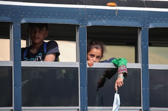 caption: Afghan evacuees sit on a bus at the U.S. air base in Ramstein, Germany, on Aug. 26. Ramstein Air Base, the largest U.S. Air Force base in Europe, has hosted thousands of Afghans.