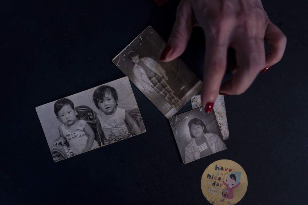 caption: Yooree Kim, who was sent to a couple in France by the Holt adoption agency when she was 11, displays some old photos of her and her brother in her apartment in Seoul, Saturday, May 18, 2024. (Jae C. Hong/AP)