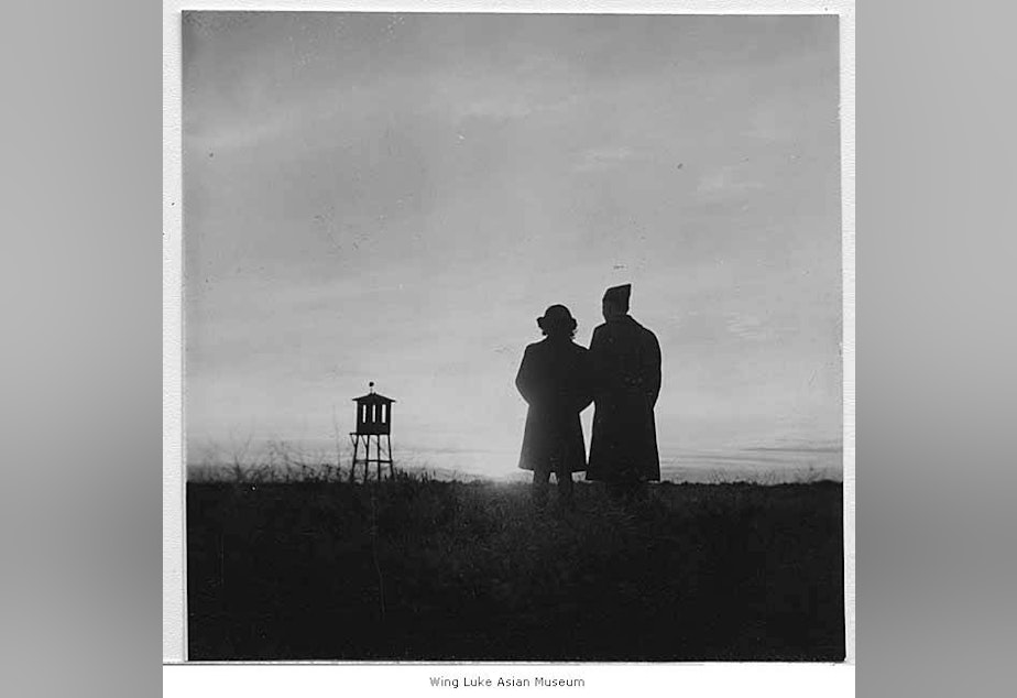 caption: Woman and soldier watching sun set behind Minidoka watchtower in Idaho, 1944.