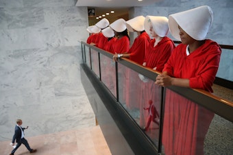 caption: Protesters dressed as characters from <em>The Handmaid's Tale</em> outside the confirmation hearing for Brett Kavanaugh on Tuesday.