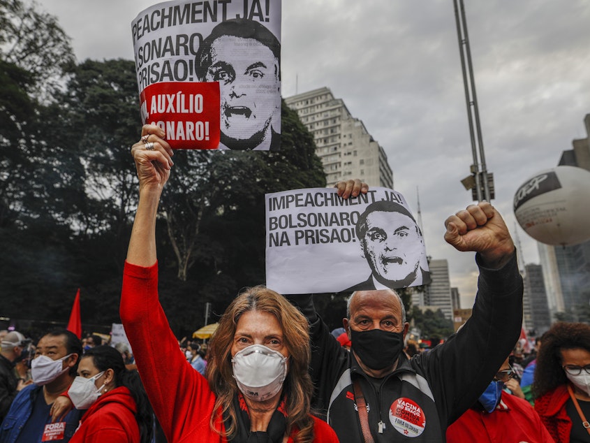 caption: Demonstrators hold signs that read in Portuguese: "Impeachment now! Bolsonaro in prison" during a protest against Brazilian President Jair Bolsonaro and his handling of the COVID-19 pandemic, in Sao Paulo, Brazil, on Saturday.