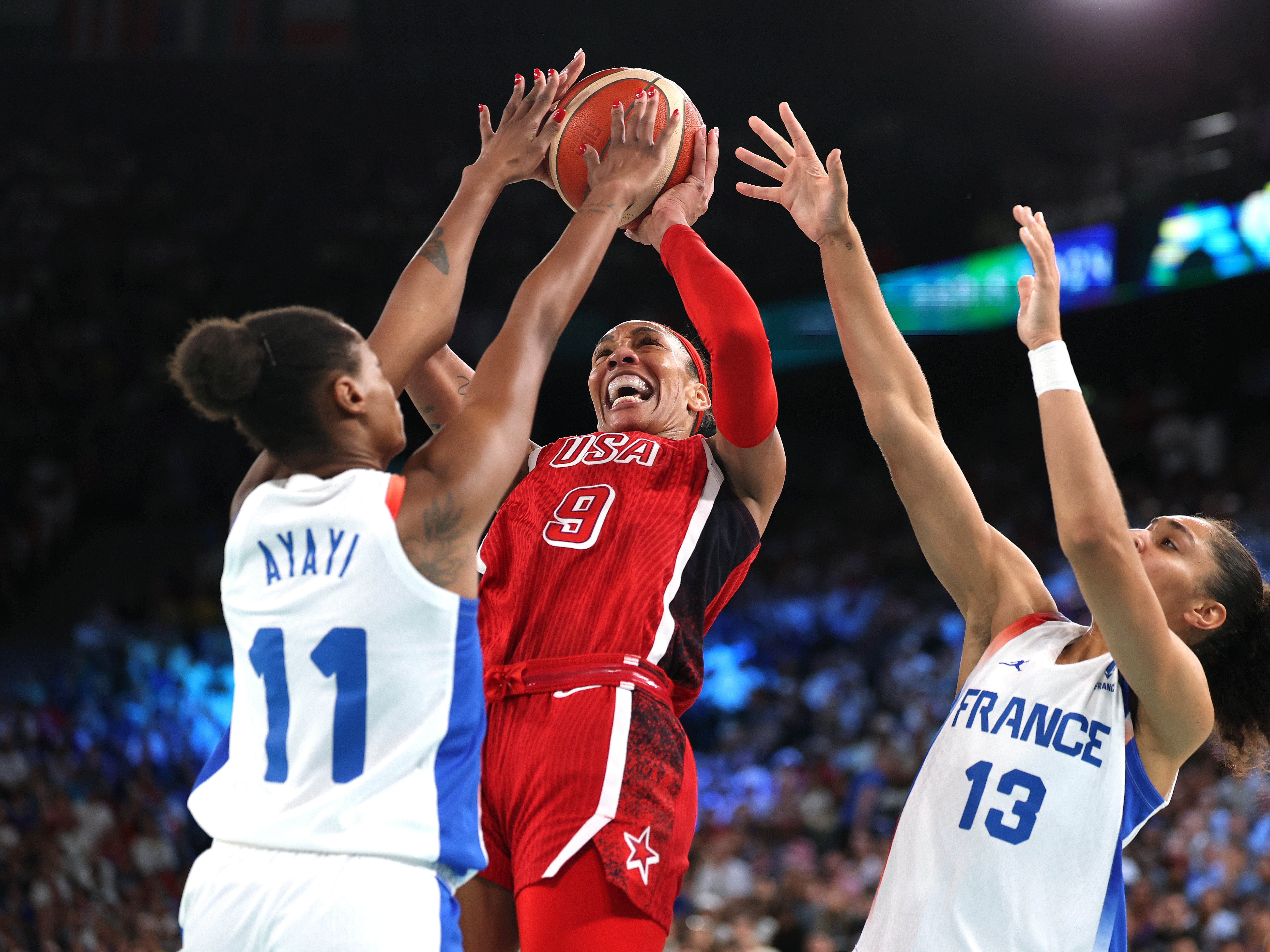 caption: A'Ja Wilson #9 of Team United States shoots between Valeriane Ayayi (L) and Janelle Salaun of Team France during the Women's Gold Medal game Sunday at the Paris Olympics.