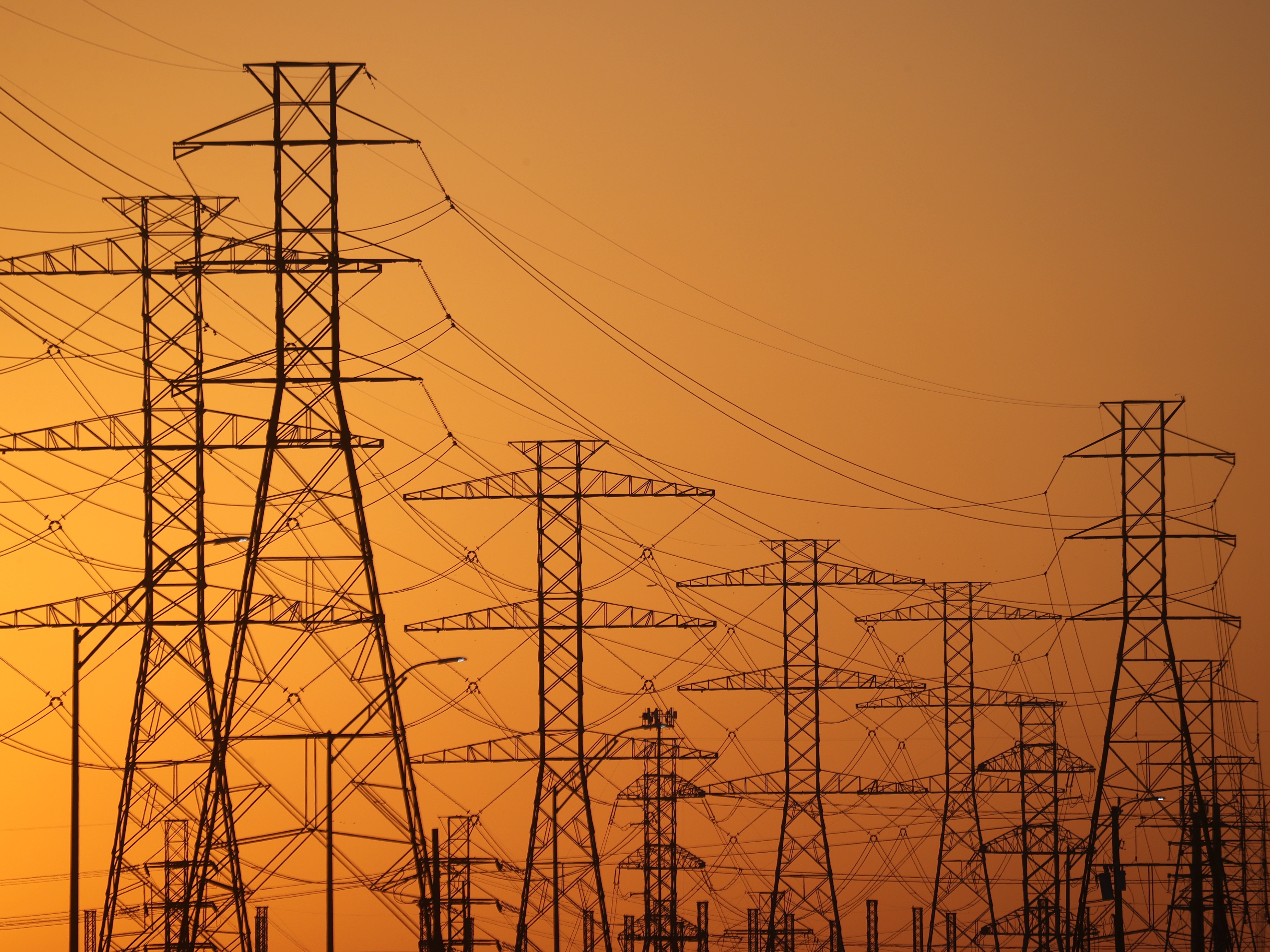 caption: A view of high-voltage transmission towers in Houston. The law President Trump signed on July 4 ends tax incentives for wind and solar projects and is expected to drive up electricity bills across the U.S., according to a nonpartisan think tank.