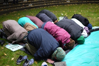 caption: Muslims and non-muslims pray together in Seattle as travel ban 3.0 is put on hold.