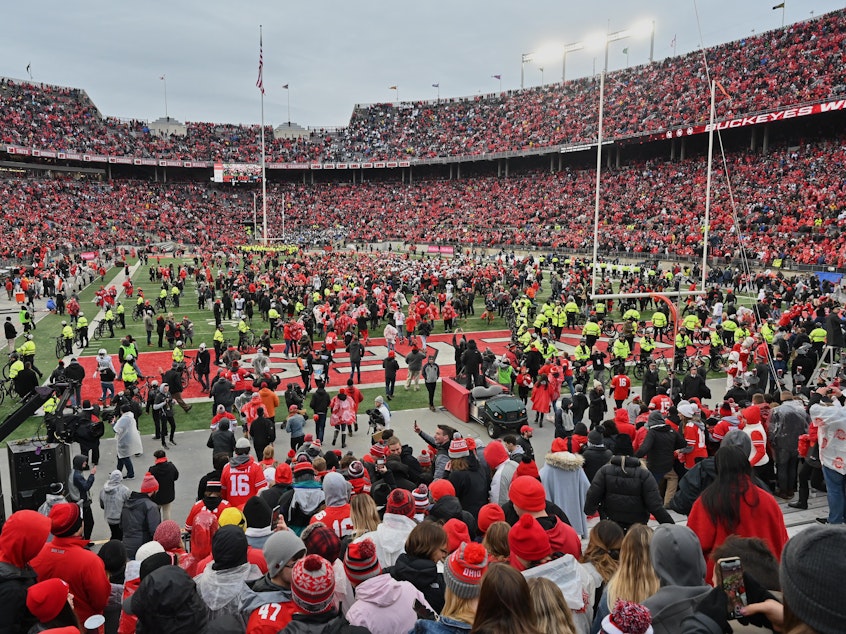 caption: Fans rush the field after the Ohio State Buckeyes defeat the Penn State Nittany Lions 28-17 in November in Columbus, Ohio. The Big Ten and PAC-12 have put fall sports on hold due to the pandemic.