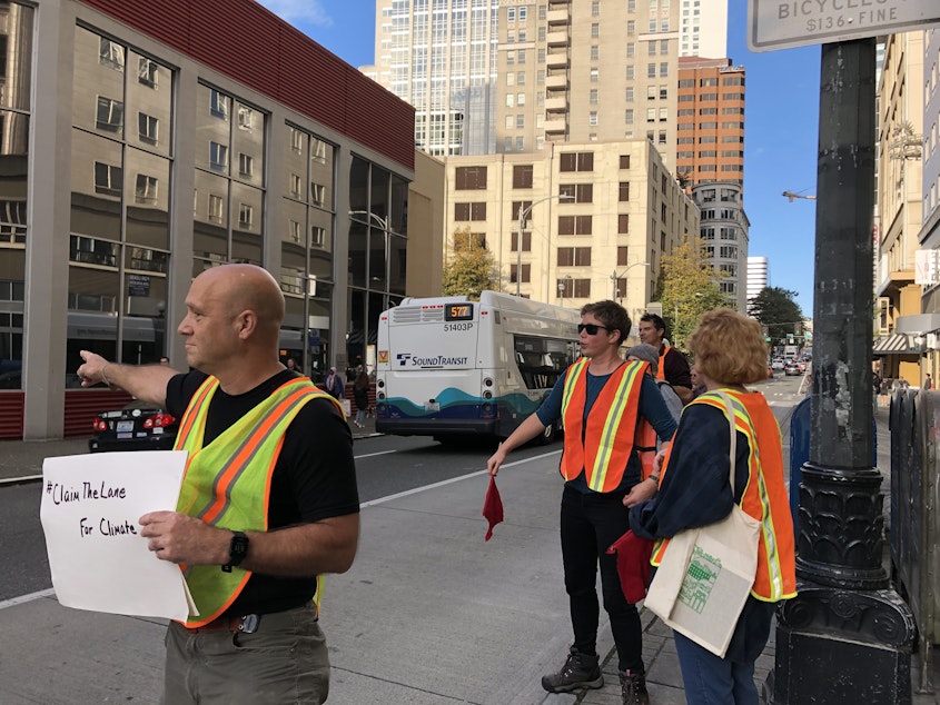 caption: Climate activists shoo car drivers out of a bus-only lane in downtown Seattle in September 2019.