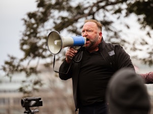 caption: Alex Jones addresses a pro-Trump crowd on Jan. 6, the day of the U.S. Capitol riot. Jones is widely known for his support of baseless and often bigoted conspiracy theories, and he has been banned from many tech platforms, though not Amazon.