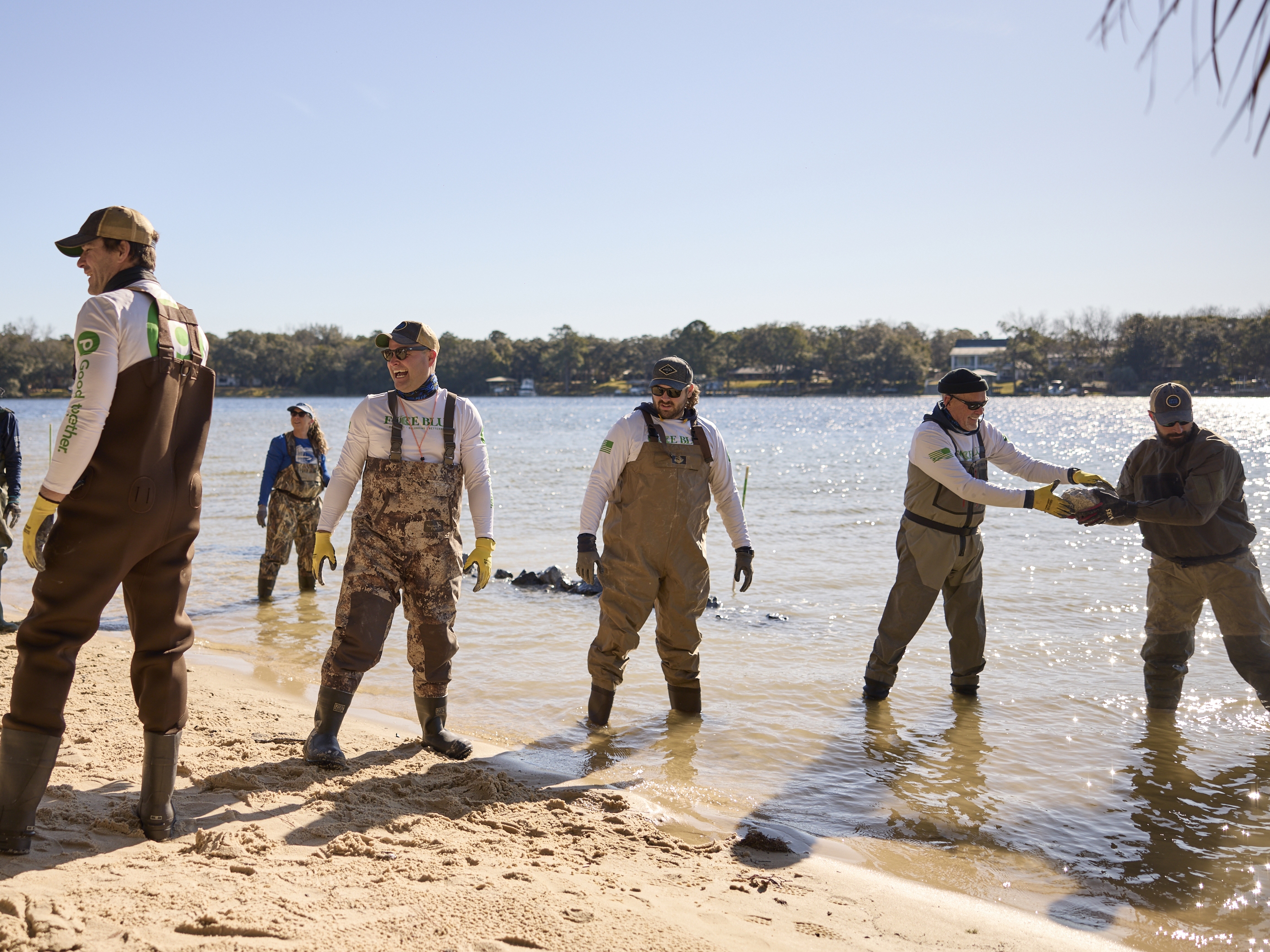caption: Veterans and volunteers with Force Blue use an assembly line to transport stones to build a rubble wall in Ft. Walton Beach, Fla.