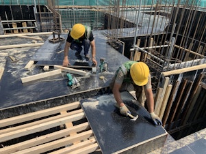 caption: Construction workers build a housing compound in Beijing.