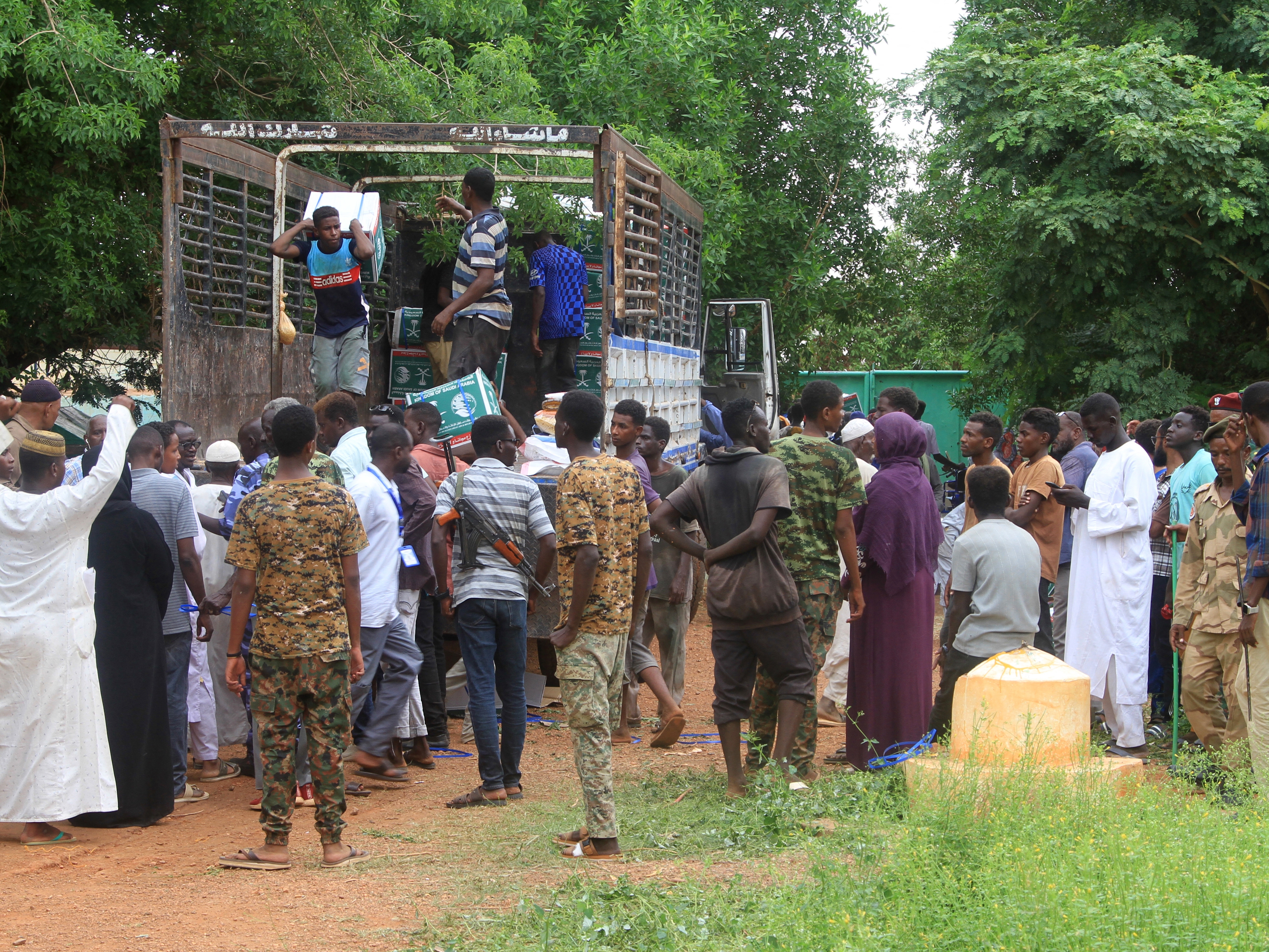 caption: In this photo from August, aid is distributed to Sudanese in Ombada, who had returned after being displaced by the ongoing civil war. As hunger has continued to mount, a global body has now declared that there is famine in Sudan.