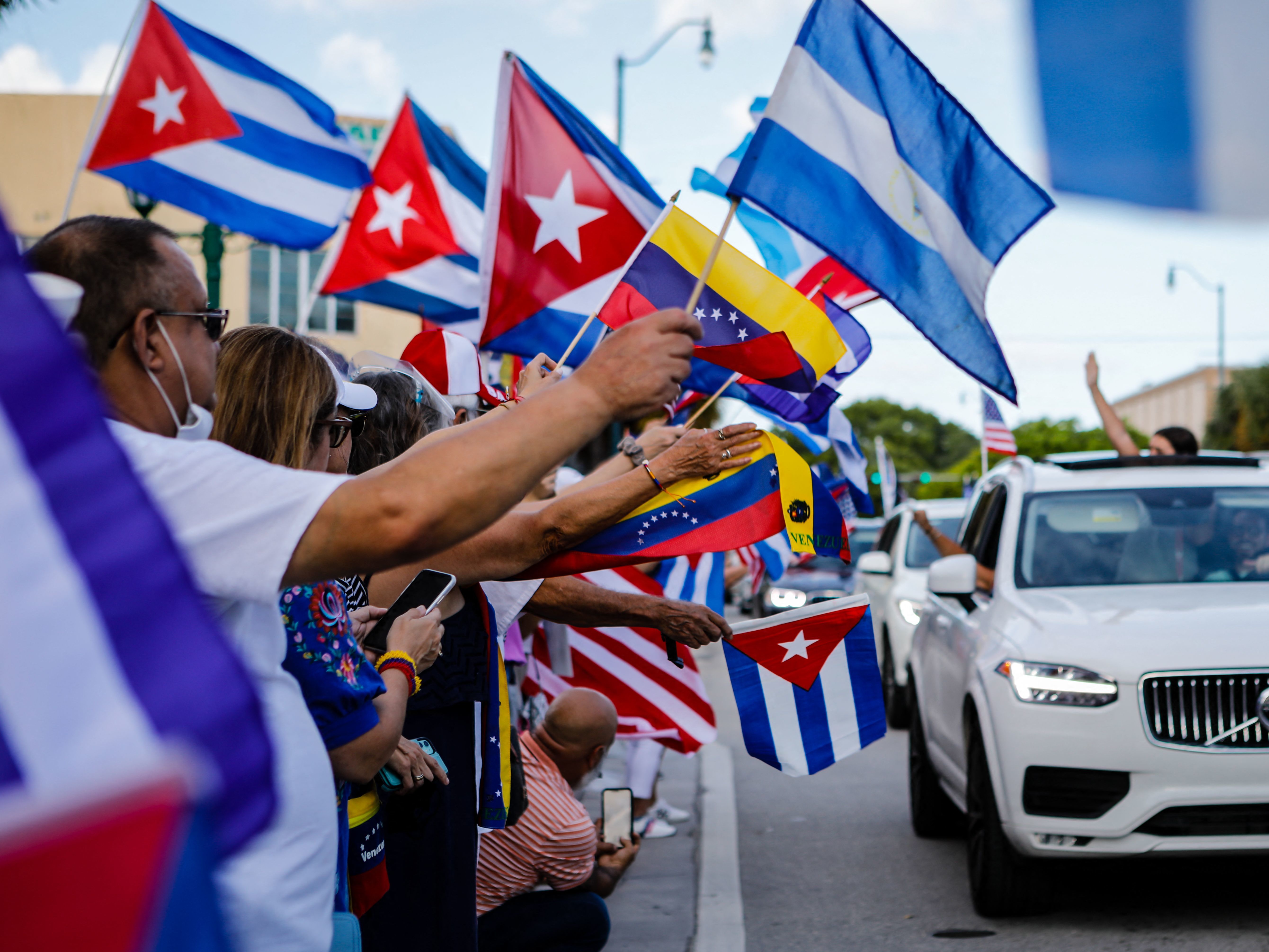 caption: People hold Cuban, Venezuelan and Nicaraguan flags during a protest showing support for Cubans demonstrating against their government in Miami on July 18. The US. Latino population has grown significantly in the last decade.