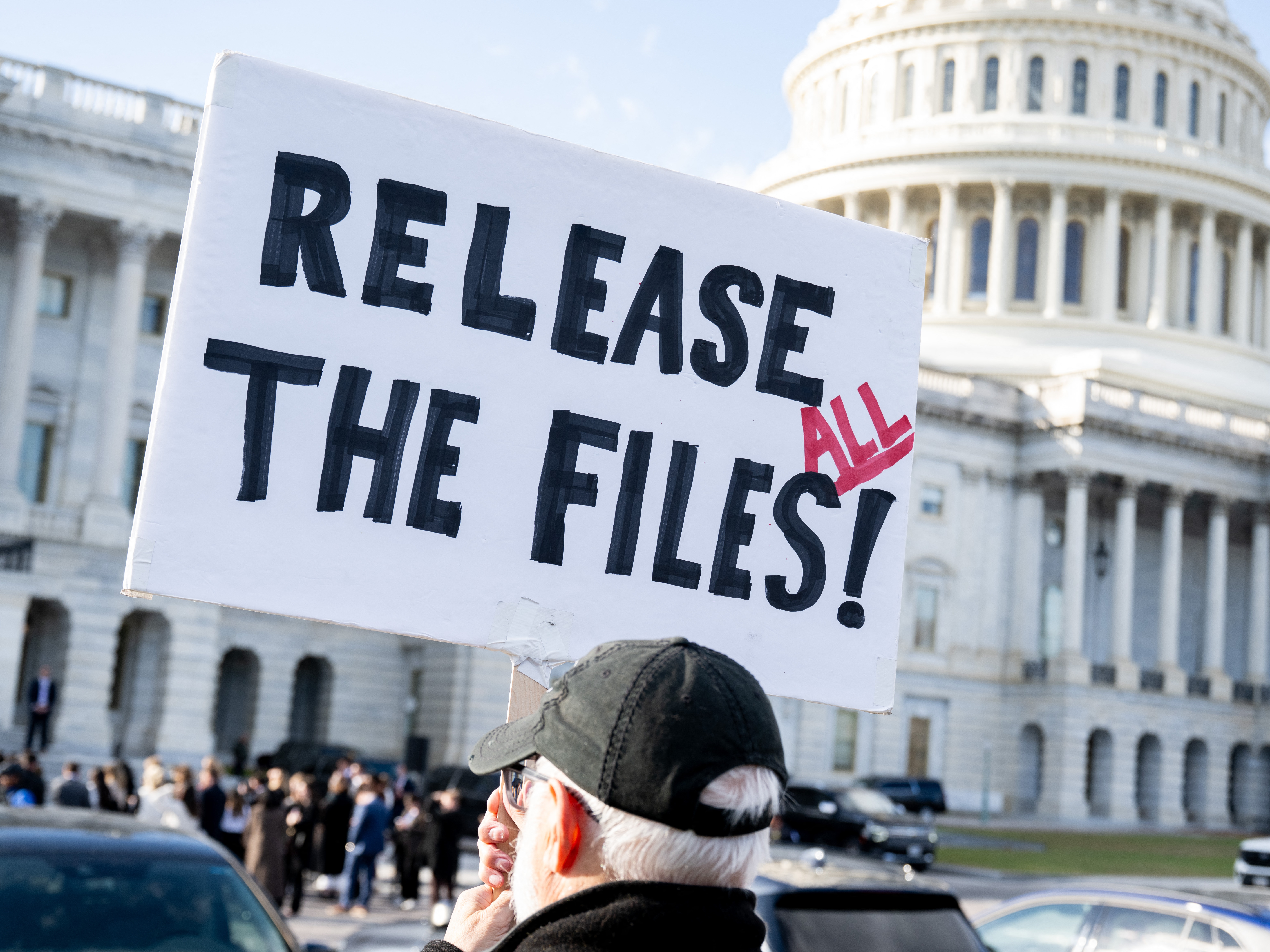 caption: A protester holds a sign related to the release of the Jeffrey Epstein case files outside the U.S. Capitol on Nov. 12, 2025.