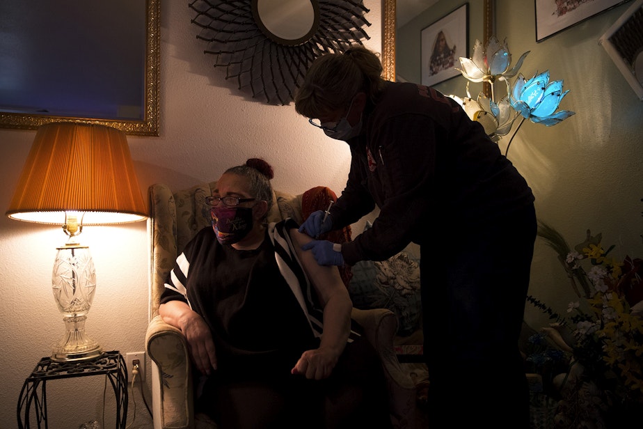 caption: Puget Sound Regional Firefighter Nikki Smith administers a Moderna Covid-19 vaccine for Jonell, a homebound individual who preferred to give her first name only, on Monday, May 24, 2021, at her home in Kent.
