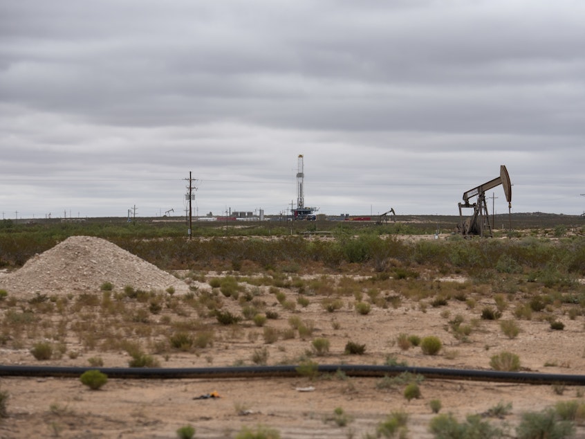 caption: A horizontal drilling rig and a pump jack sit on federal land in Lea County, N.M., in September. The state stands to lose royalties and revenue from a Biden administration pause on new oil and gas leases.