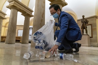 caption: Rep. Andy Kim, D-N.J., cleans up debris and trash strewn across the floor in the early morning hours of Thursday, Jan. 7, 2021, after protesters stormed the Capitol in Washington, on Wednesday, Jan. 6, 2021. 