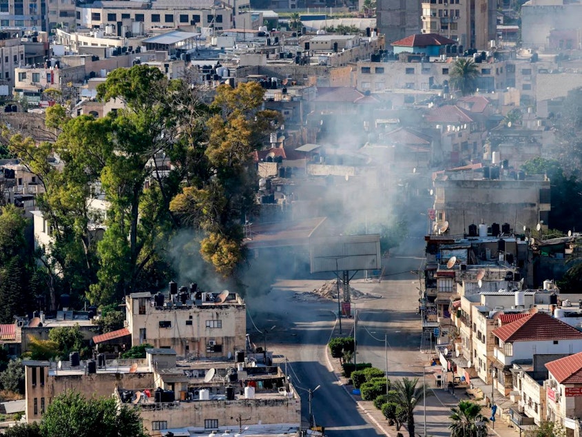caption: A cloud of smoke billows during an Israeli army raid in Jenin in the occupied West Bank on June 6. The Israeli military said it was investigating an incident in which a wounded Palestinian man was strapped to an Israeli military jeep while forces carried out "counterterrorism operations" in Jenin on Saturday.
