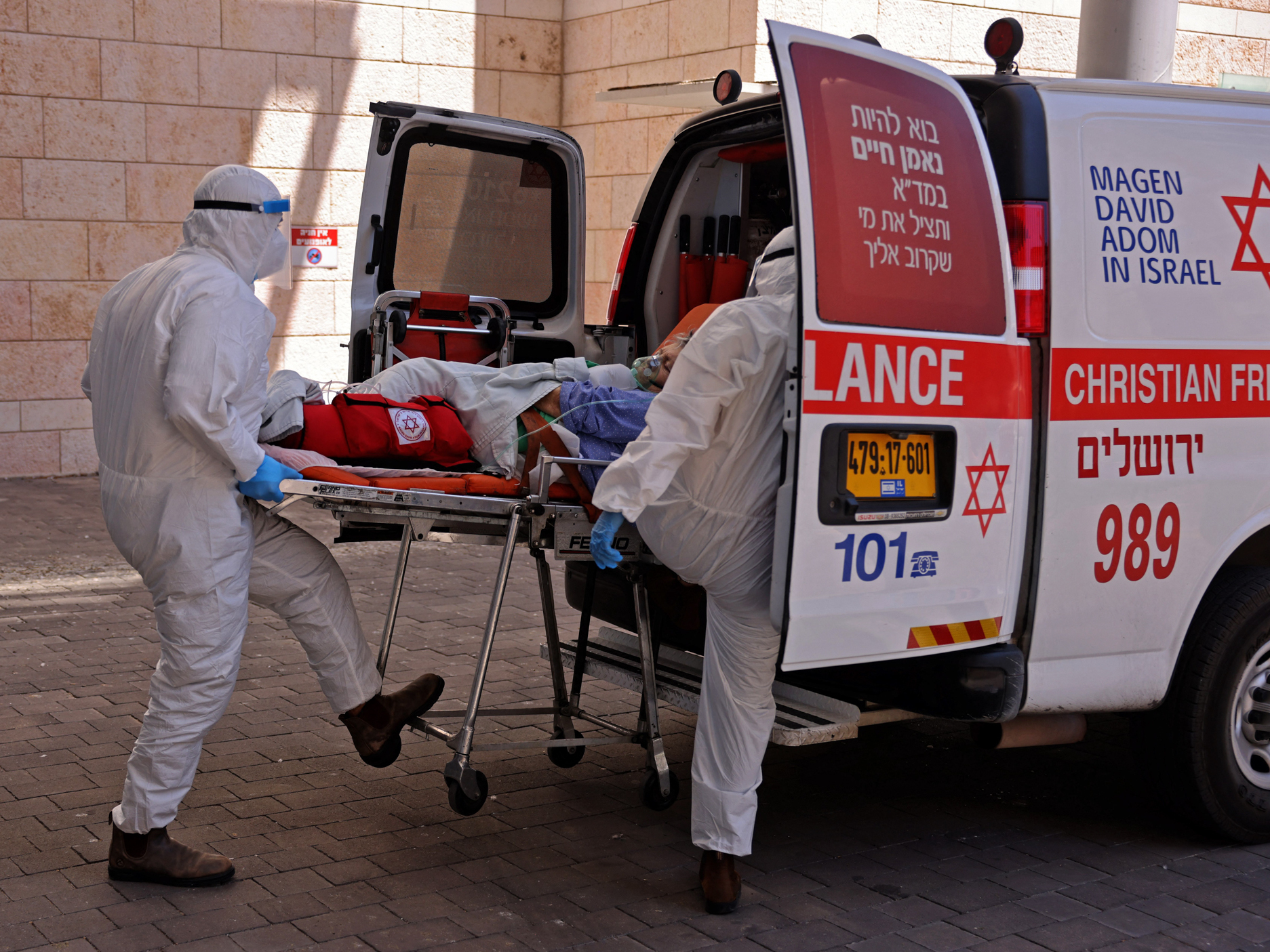 caption: Medics in Jerusalem transfer a COVID-19 patient to Hadassah Hospital Ein Kerem. Many hospitals in Israel are at full capacity following a sharp increase in coronavirus infections.