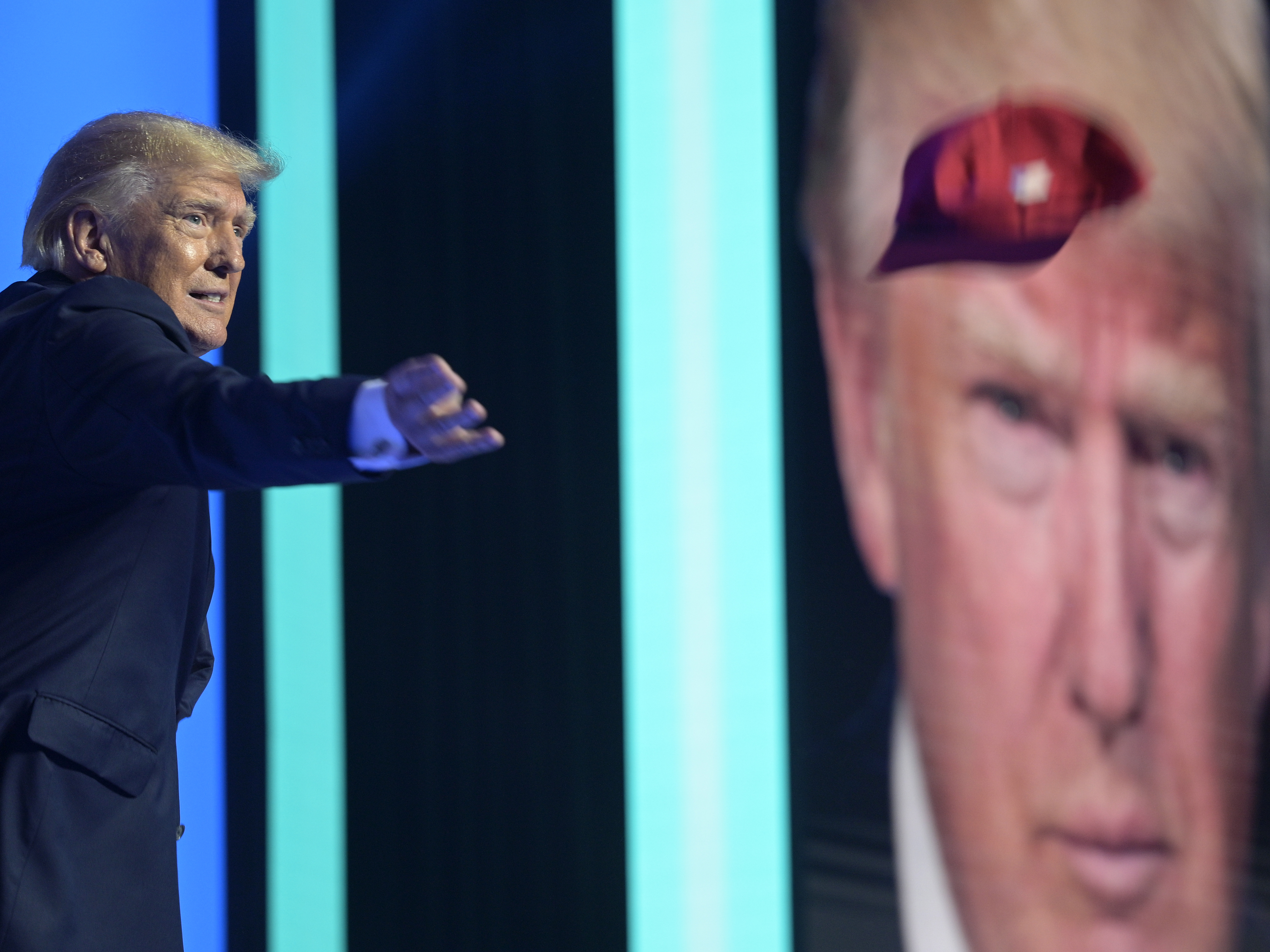 caption: Former President Donald Trump tosses hats into the crowd before addressing attendees during the Turning Point USA Student Action Summit on July 23, 2022, in Tampa, Fla.