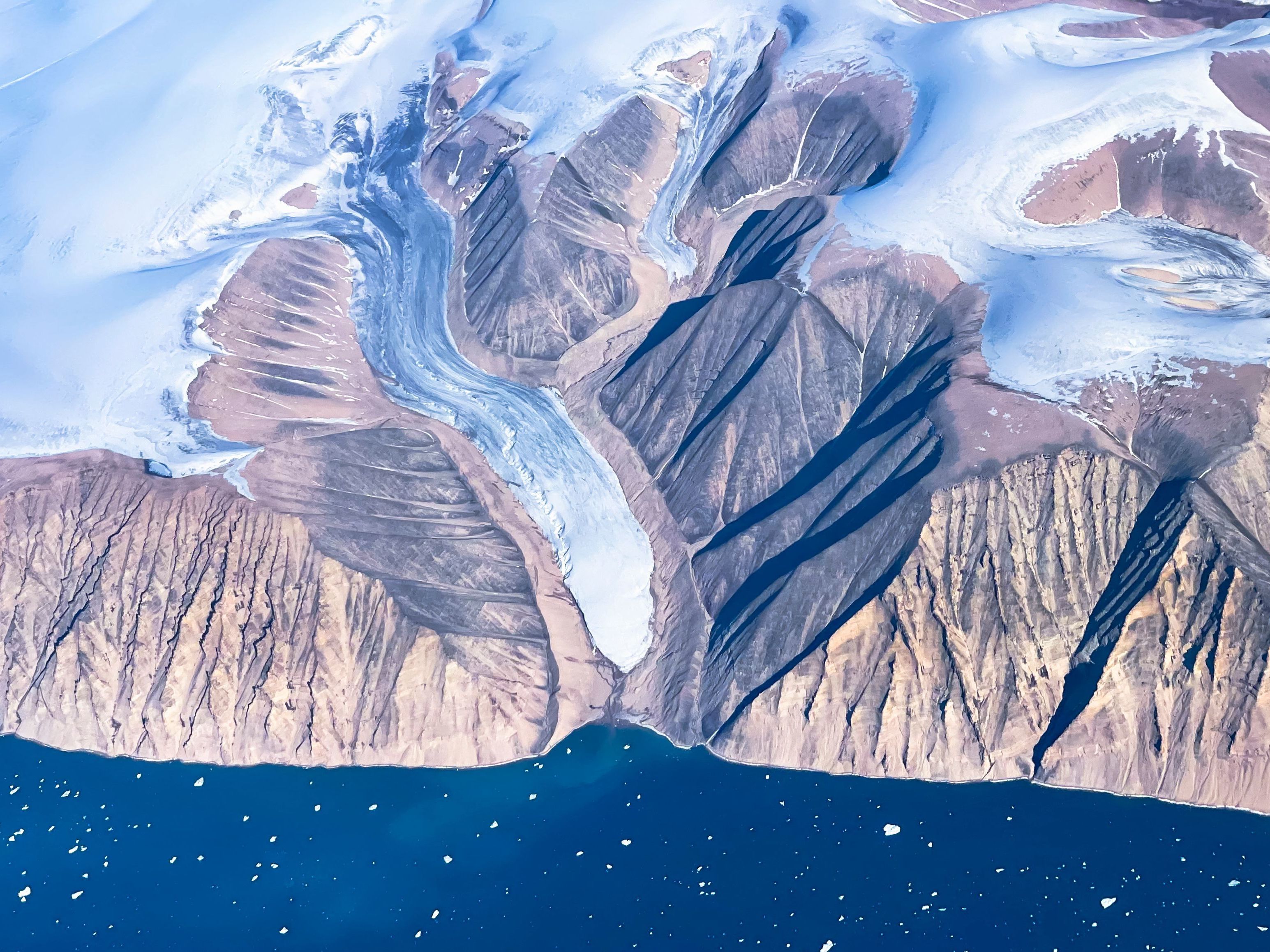 caption: An aerial view of icebergs and the ice sheet near Pituffik, Greenland.