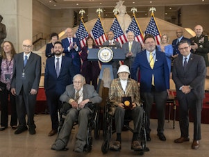 caption: Ghost Army members John Christman, of Leesburg, N.J., second from left standing, Seymour Nussenbaum, of Monroe Township, N.J, in wheelchair at left, and Bernard Bluestein, of Hoffman Estates, Ill., in wheelchair at right, join military and congressional officials as members of their secretive WWII-era unit are presented with the Congressional Gold Medal on Thursday.