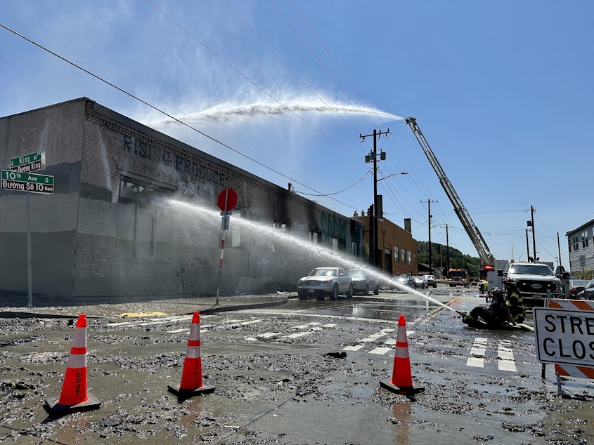 caption: Fire crews douse the flames at a vacant building in Seattle's Chinatown-International District on July 20, 2023.