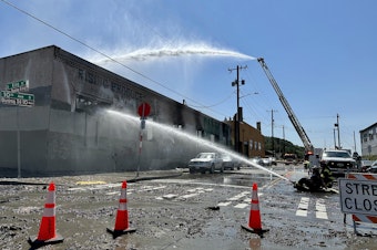 caption: Fire crews douse the flames at a vacant building in Seattle's Chinatown-International District on July 20, 2023.