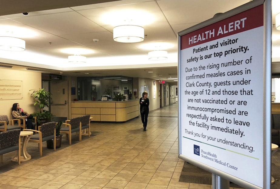 caption: A sign prohibiting all children under 12 and unvaccinated adults stands at the entrance to PeaceHealth Southwest Medical Center in Vancouver, Wash. CREDIT: GILLIAN FLACCUS/AP