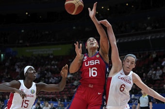 caption: The United States' Brionna Jones (center) is fouled by Canada's Bridget Carleton, (right) during their semifinal game at the women's Basketball World Cup in Sydney on Friday.