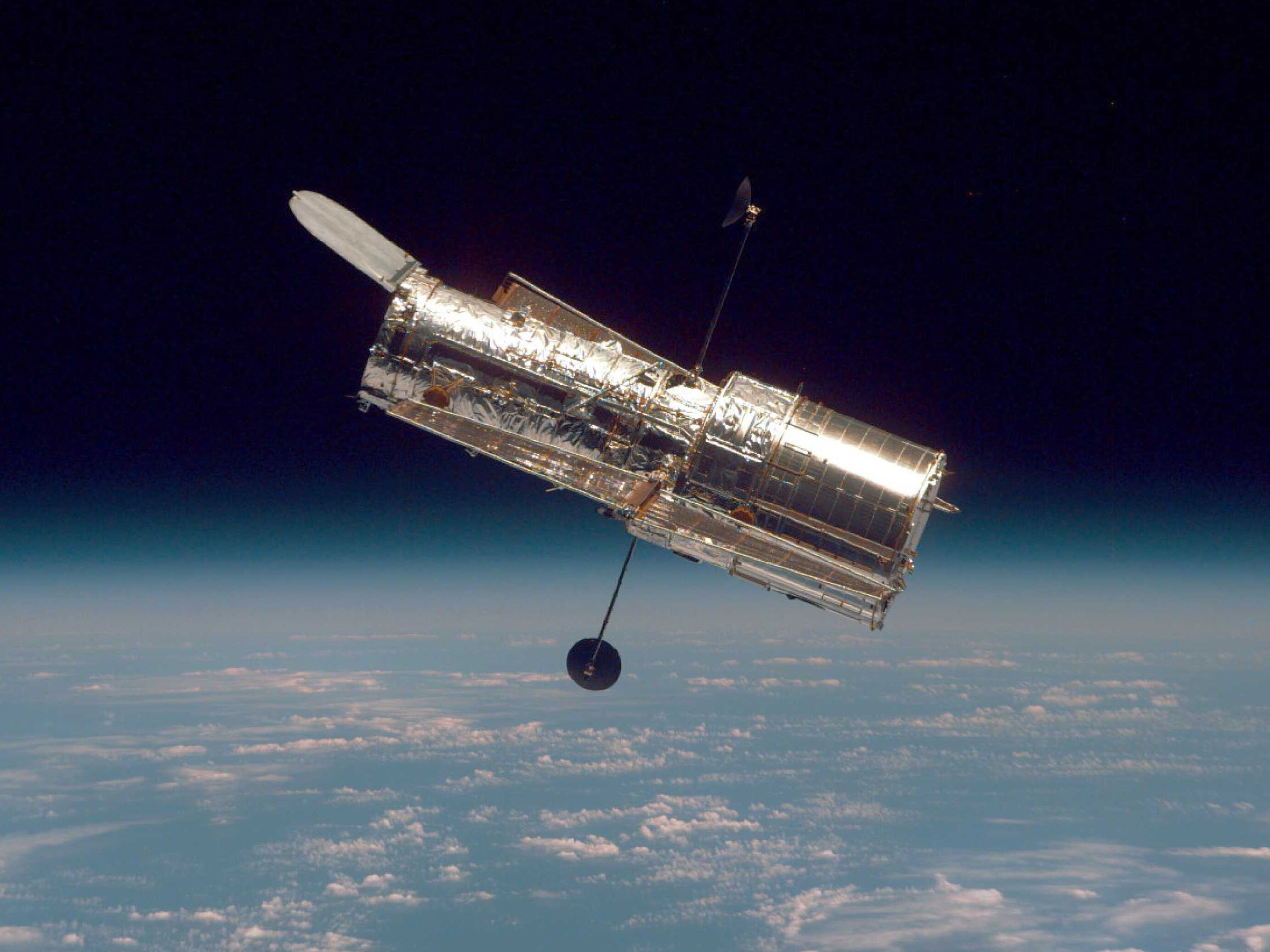 caption: The Hubble Space Telescope drifts through space in a picture taken from the Space Shuttle Discovery in 1997. A study finds reflections cast by satellites could ruin images taken by telescopes.