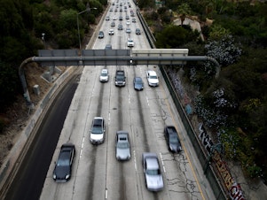 caption: Cars drive down the 110 Freeway toward downtown Los Angeles, California in April 2021. President Biden has pledged to cut U.S. greenhouse gas emissions in half by 2030.